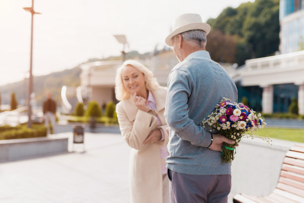 一位老人背后拿着一束花。一个女人来约会，并试图窥探隐藏男人的东西图片下载