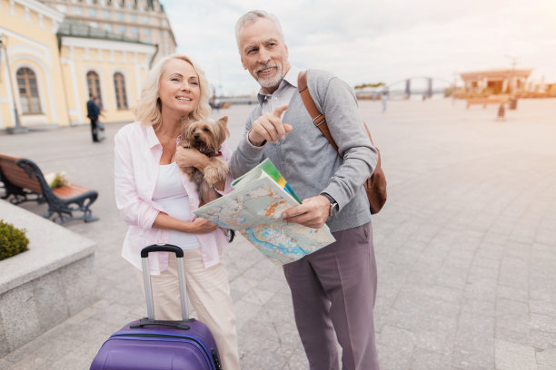 一对老夫妇带着他们的小狗沿着堤岸散步。他们带着一个紫色的旅行袋去了图片下载