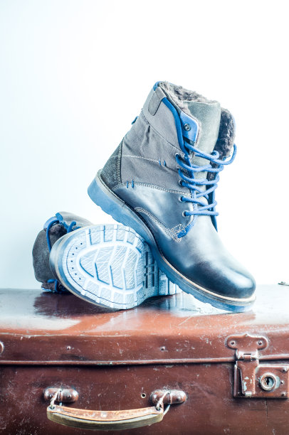 男人冬天的鞋子放在旧的手提箱前面，背景是白色的图片下载