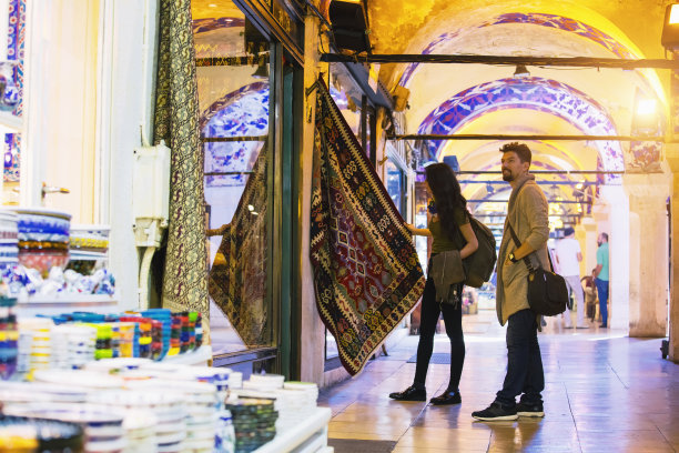 一对年轻的游客夫妇在土耳其伊斯坦布尔的大巴扎购买地毯图片下载