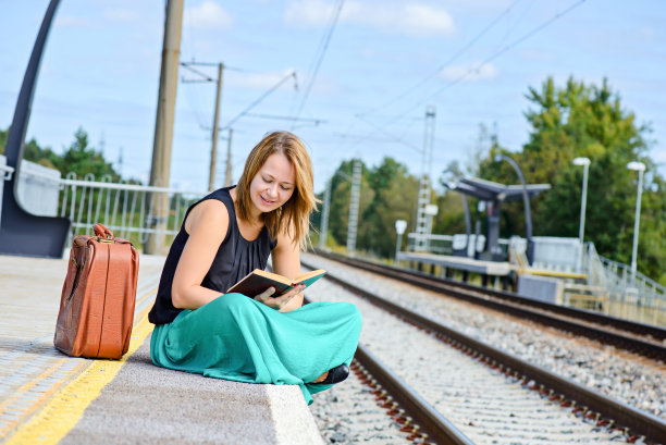 一个女人坐在车站上看书图片下载