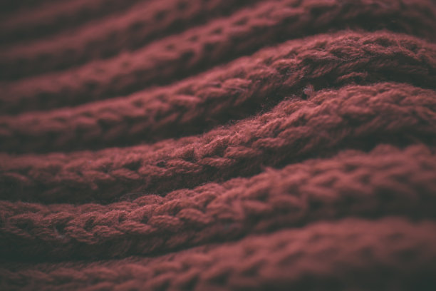 红色复古针织面料的质地和背景为设计师。复古编织的背景。红色抽象纹理的近景。暗红色的复古布料。深红色针织图案。图片下载