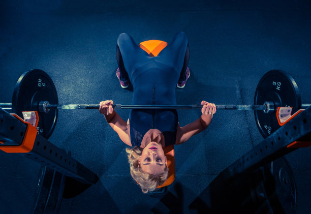 健康的年轻女子举着杠铃，看起来很专注，在健身房锻炼图片下载