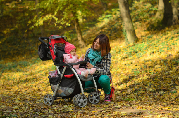 年轻的母亲带着她的婴儿走在婴儿车里图片下载