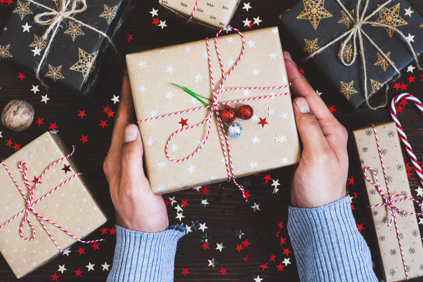 男人手捧圣诞礼盒放在装饰好的节日桌上图片下载