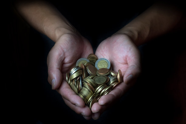 男人手里拿着金币。储蓄，金钱，财务捐赠，捐赠和商业概念。黑色背景。心的形状。图片下载