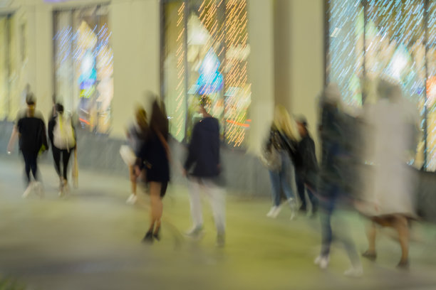 抽象模糊的图像无法辨认的剪影的人走在城市的街道在晚上，购物。城市现代化的背景。模糊效果图片下载