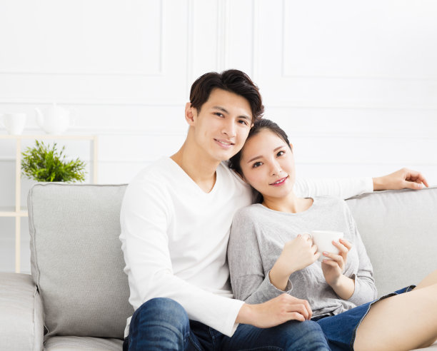 放松的年轻亚洲夫妇在沙发上素材图片