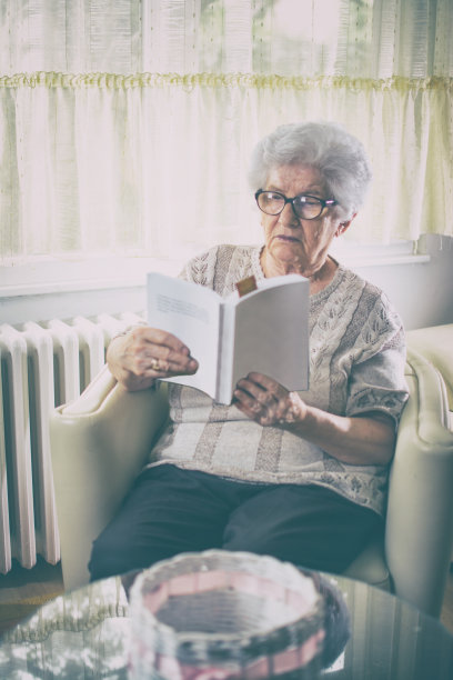 复古风格的照片，年长妇女坐在扶手椅和读书。图片下载