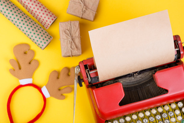 假日概念-红色打字机与空白牛皮纸，礼品盒在黄色背景图片下载