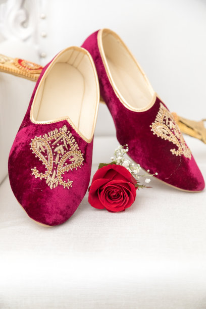 传统的印度新郎的红色婚礼鞋，背景上有剑。图片下载