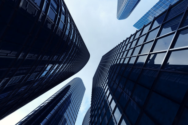 摩天大楼的低角度视图。日落时仰望摩天大楼的视角。在傍晚日落时，在商业区的现代摩天大楼的底部视图。商业理念的成功行业技术架构。图片下载