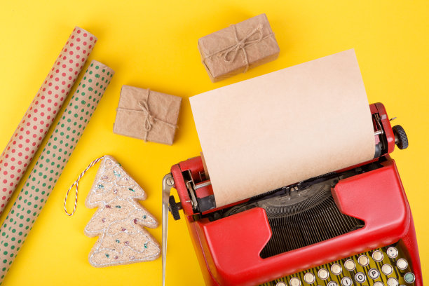 假日概念-红色打字机与空白牛皮纸，礼品盒和包装纸在黄色背景图片下载