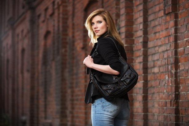 年轻时尚的金发商务女人拿着手提包走在城市的街道上图片下载