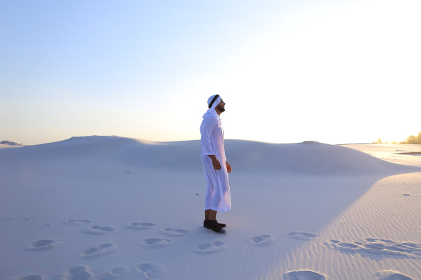自信的阿拉伯男子在白色沙漠中行走图片下载