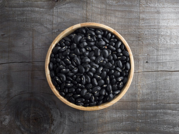 木碗里放黑豆，木勺里放黑豆，背景是木头图片下载