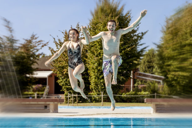一对年轻的恋人在游泳池里跳图片下载