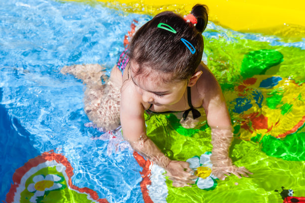 可爱的，快乐的，微笑的学步的小女孩，游泳，玩在多彩的充气后院游泳池在炎热的夏天。图片下载