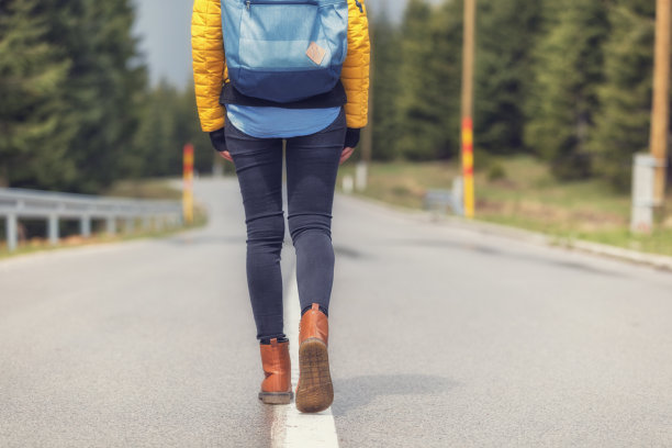 女孩走在郊区空旷的路上。图片下载
