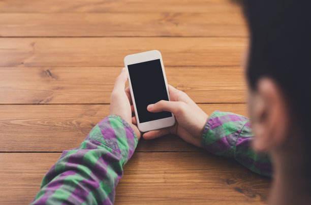 在木头背景下使用智能手机的男子，特写图片下载