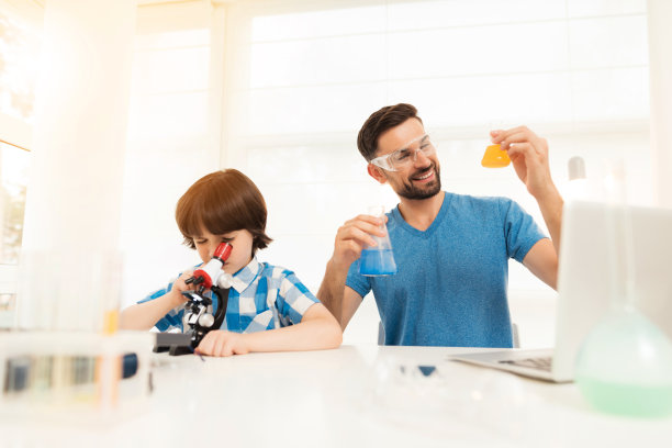 父亲和儿子在家里进行化学实验。图片下载