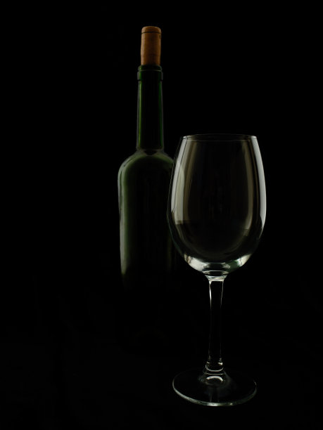 黑色背景上的一瓶葡萄酒和一个酒杯。图片下载