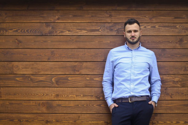 一个英俊男子的肖像在一个木制的墙壁背景衬衫。商人，穿着时髦的老板。设计素材照片图片下载