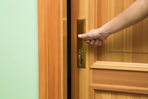 女人的手打开木门。素材图片