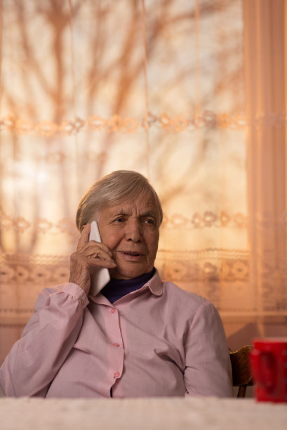 快乐的老女人在家里用手机聊天。图片下载