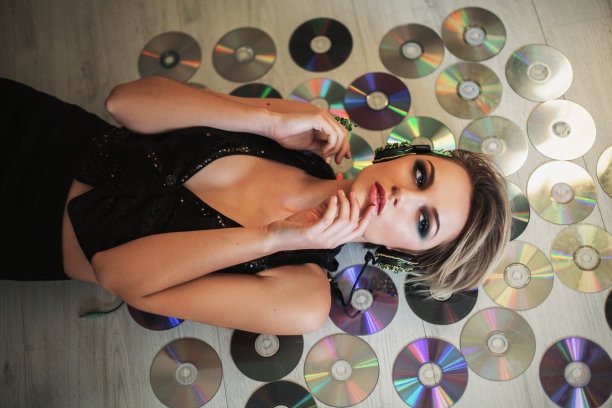 可爱的女孩，皮肤黝黑，头发白皙，戴着耳机听音乐，躺在碟片上。女性美妆画像美妆。享受好音乐图片下载