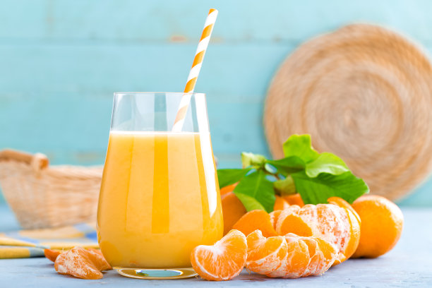 橘子，去皮的橘子和橘子汁在玻璃杯里。橘子汁和带叶子的新鲜水果。图片下载