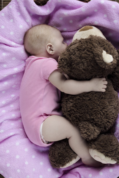 抱着洋娃娃睡觉的新生婴儿图片下载