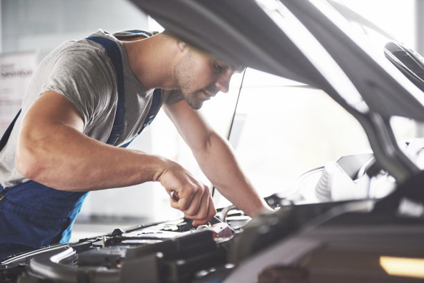 图片显示肌肉发达的汽车服务人员正在修理汽车图片下载