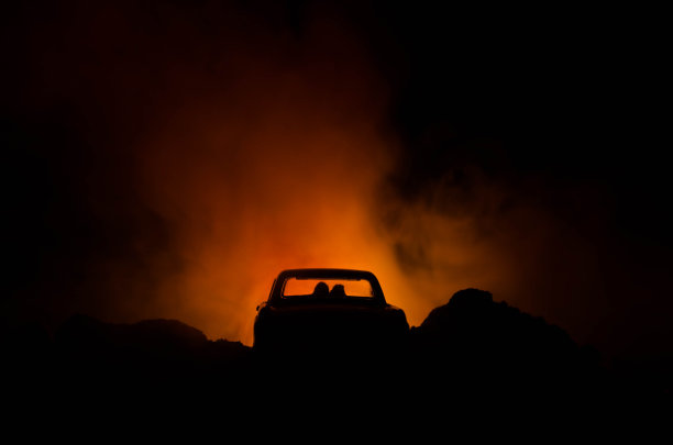 汽车的轮廓与夫妇在黑暗的背景与灯光和烟雾。浪漫的场景。爱的概念图片下载