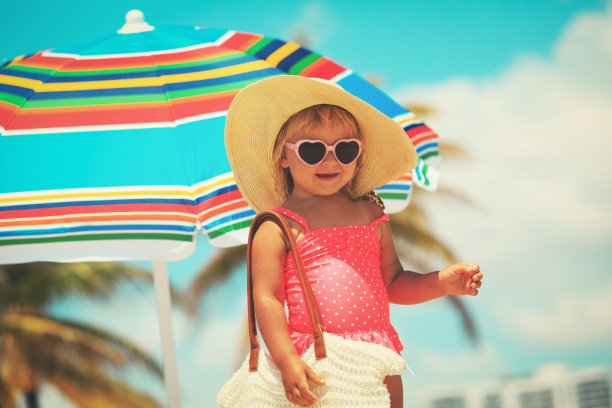 可爱的小女孩拿着大袋子在海滩上图片下载