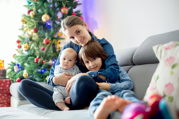 母亲，抱着她的两个孩子，坐在沙发上图片下载