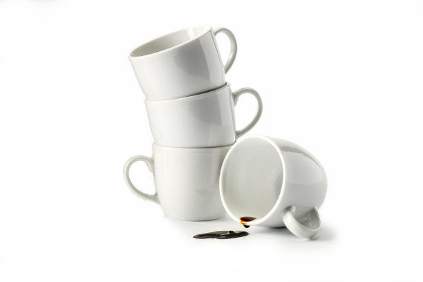 咖啡:咖啡滴在一个杯子里，滴和杯子孤立在一个白色的背景上图片下载