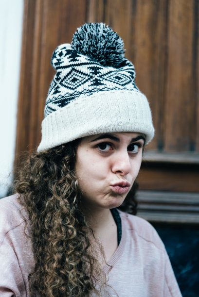 长而卷的头发戴一顶针织帽的少女图片下载
