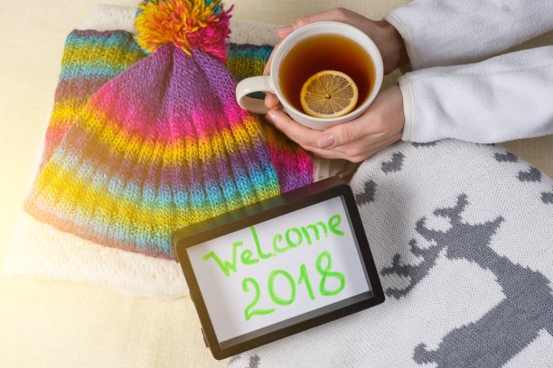 欢迎2018，文字在框中。冬季服装背景和一杯柠檬热茶。图片下载