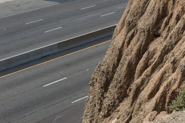 背景公路采用混凝土分隔带和极陡的土质山坡，侵蚀严重，有滑坡隐患图片下载