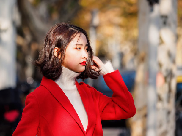 身穿红色外套的年轻美丽黑发女子在秋季城市中，街头时尚魅力中国时尚女士的户外时尚肖像。素材图片