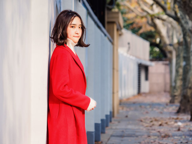 身穿红色外套的年轻美丽黑发女子在秋季城市中，街头时尚魅力中国时尚女士的户外时尚肖像。素材图片