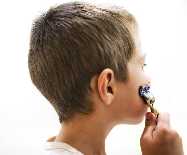 小男孩刮了他爸爸的剃刀，看着镜子图片下载