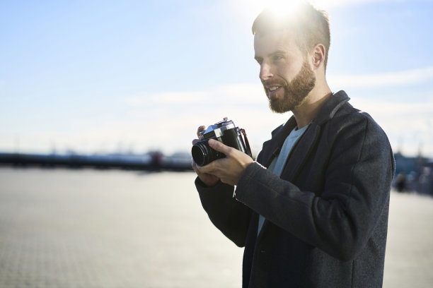 专业的有才能的男性摄影师用老式相机思考摄影的概念，潮人站在你的广告复制空间区域拍摄城市设置的照片图片下载