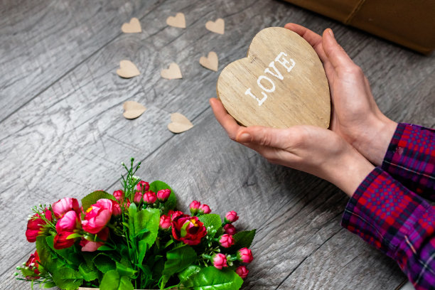 女人手里拿着一颗木制的心，情人节，浪漫的照片。带礼物和一束鲜花，带爱心和礼物，适合做广告图片下载