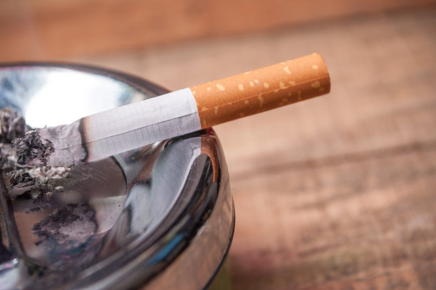 烟灰缸上的香烟在木制背景上图片下载