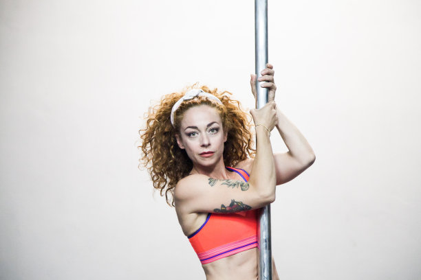 在钢管舞训练中，红头发的女孩身材健壮图片下载