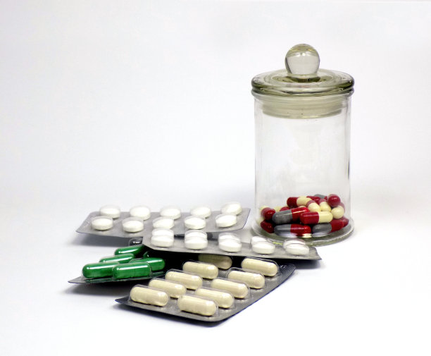 药片、药品和胶囊装在复古风格的玻璃罐里，药片的包装在旁边图片下载