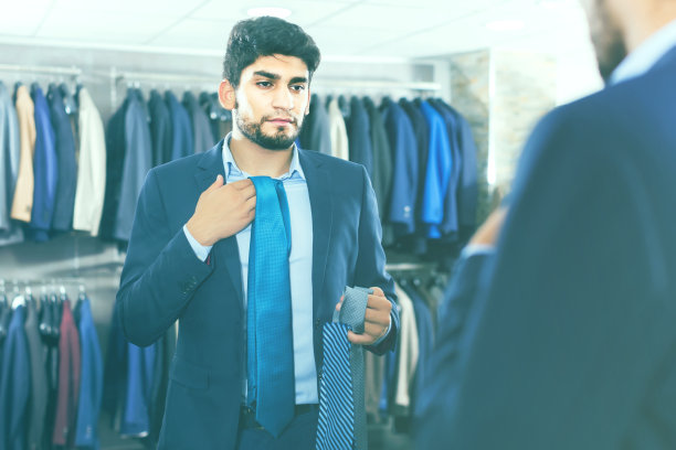 一名男子在镜子前拿起西装领带图片下载