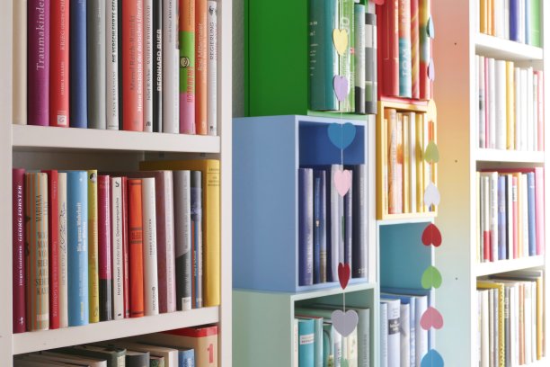 五颜六色的图书馆书架上塞满了书，彩色的纸心挂在书上图片下载
